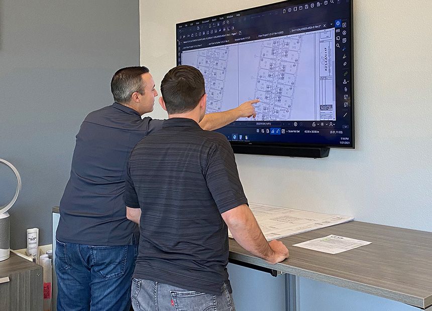Two men looking at drawings on monitor